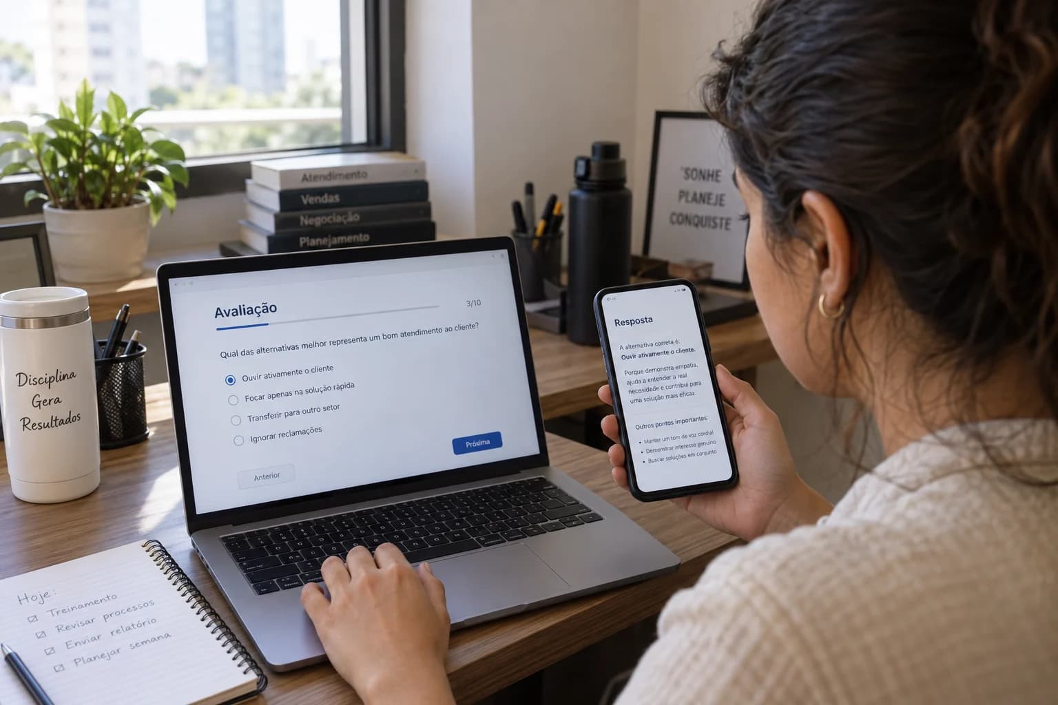 Participante consulta una respuesta en el celular mientras completa una evaluación en la computadora.